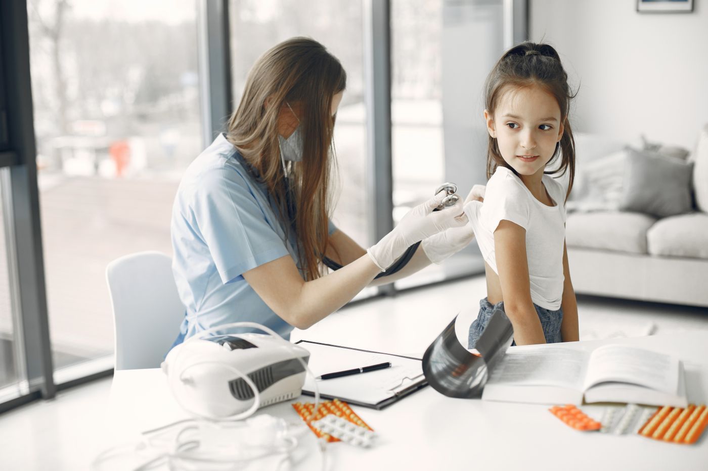 Pediatra revisando a una niña con estetoscopio